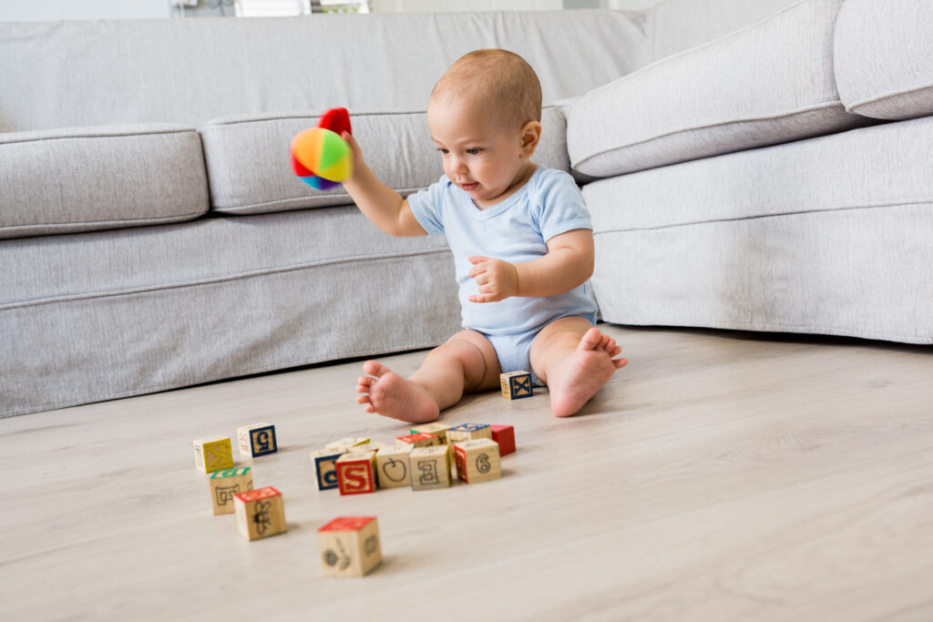 baby boy sitting on floor and playing with toys in living room